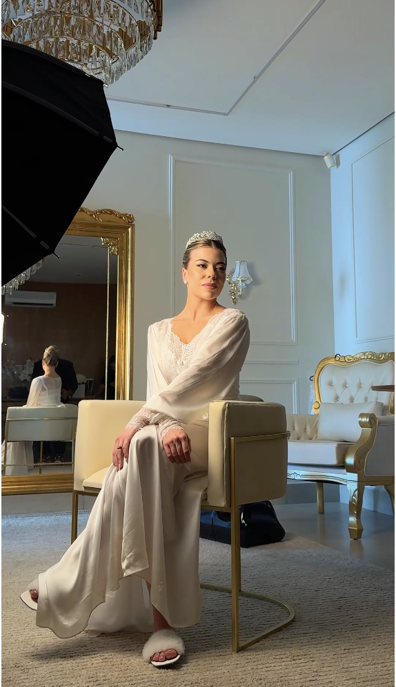 Noiva sentada em bastidor de casamento, iluminada por luz quente.